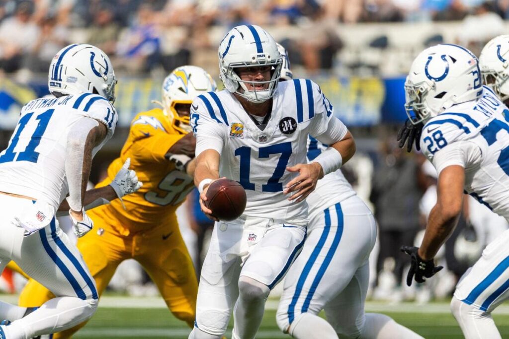 O quarterback do Indianapolis Colts, Daniel Jones, entregando uma bola de futebol durante um jogo.