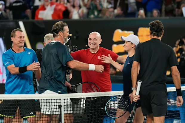 Andre Agassi dos Estados Unidos abraça Ash Barty, segundo à direita, Lleyton Hewitt, à esquerda, e Pat Rafter enquanto Roger Federer, à direita, observa após uma partida de duplas durante a Cerimônia de Abertura do campeonato de tênis do Aberto da Austrália em Melbourne, Austrália, sábado, 17 de janeiro de 2026. (AP Photo/Aaron Favila)