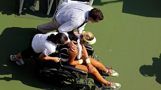 Victoria Azarenka, da Bielo-Rússia, é retirada da quadra em uma cadeira de rodas após desmaiar.