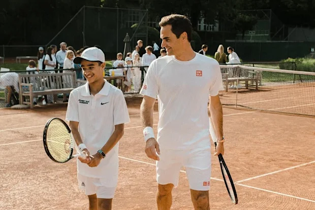 Izyan 'Zizou' Ahmad posa com Roger Federer na quadra.