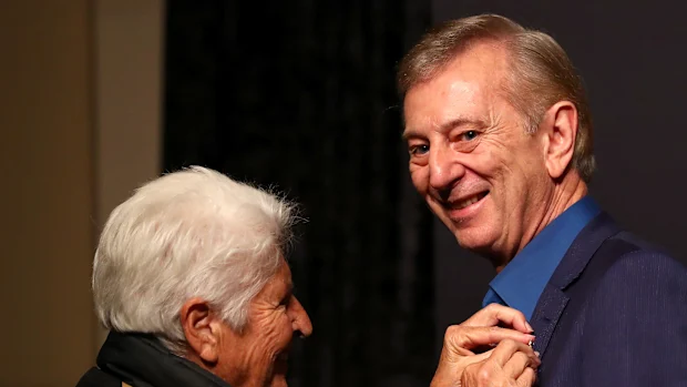 Dennis Cometti recebe um prêmio de Dawn Fraser durante a introdução ao Hall da Fama do Sport Australia em 2019.