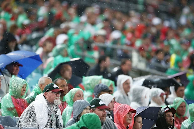Os fãs dos Rabbitohs sentam-se na chuva.