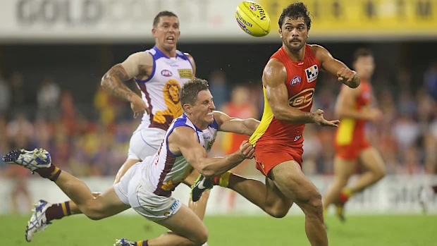 Karmichael Hunt, do Suns, joga handebol enquanto é abordado por James Polkinghorne, do Lions.