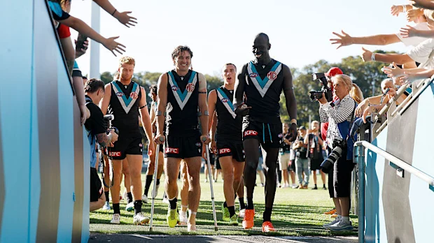 Connor Rozee deixa o campo de muletas enquanto se junta aos companheiros para comemorar a vitória.