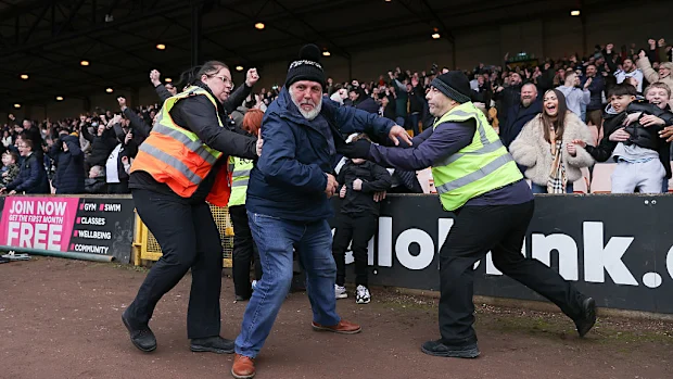 Os comissários tentam impedir que um torcedor do Port Vale invada o campo na partida contra o Sunderland.