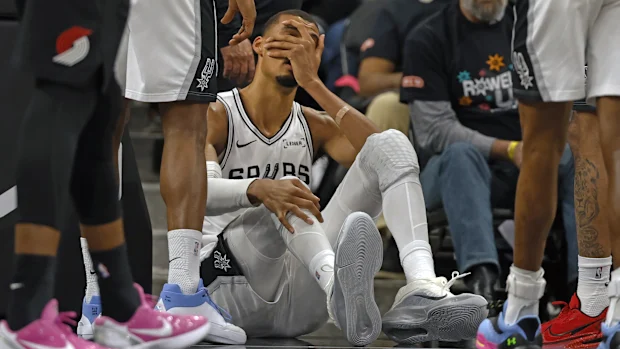 Victor Wembanyama segura a cabeça após cair na quadra.