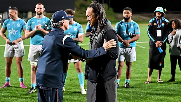 O técnico dos Reds, Les Kiss, e o capitão Fraser McReight apresentam o aborígine australiano nulla nulla para Tana Umaga e Miracle Faiilagi.