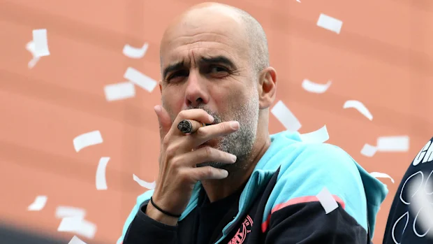 Pep Guardiola fuma um charuto.
