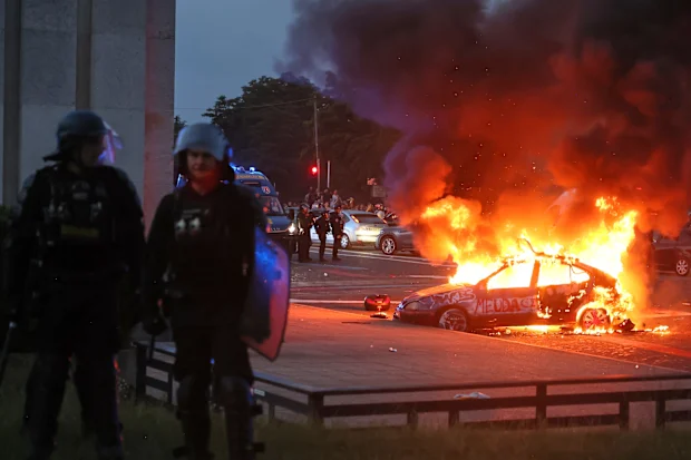 Um carro pega fogo enquanto torcedores do PSG comemoram em Paris.