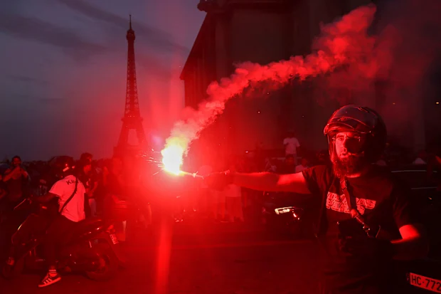 Um homem segura um sinalizador enquanto os torcedores do PSG comemoram em Paris.