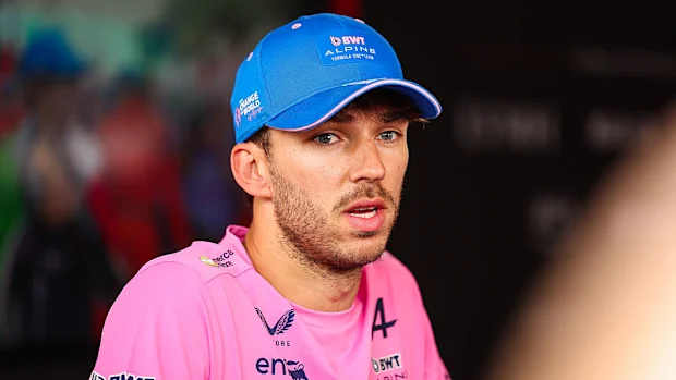 Um homem com uma camisa rosa da Alpine F1 fala à mídia.