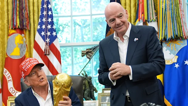 O presidente Donald Trump segura o Troféu dos Vencedores da Copa do Mundo da FIFA enquanto o presidente da FIFA, Gianni Infantino, observa.
