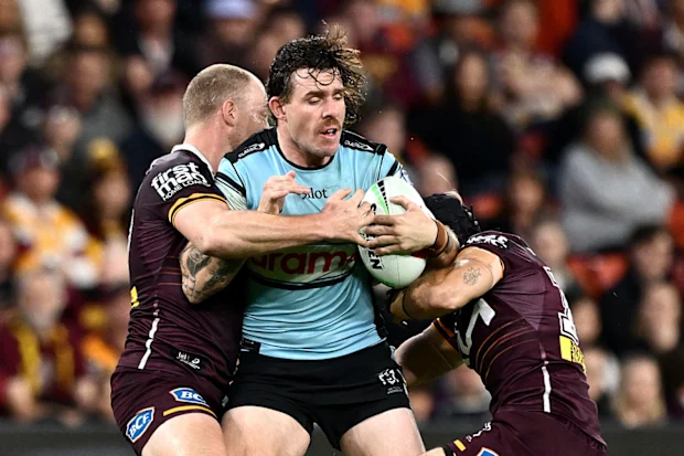 Billy Burns dos Sharks é abordado durante a partida da 18ª rodada da NRL entre Brisbane Broncos e Cronulla Sharks no Suncorp Stadium, em 4 de julho de 2026, em Brisbane, Austrália. (Foto de Bradley Kanaris/Getty Images)