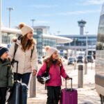 Family with skis and suitcases walking to a pre-booked ski transfer minibus at the airport